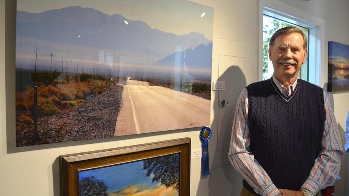Clyde Lohere stands next to his “Best In Show” winning photograph, “The Road Home.”
