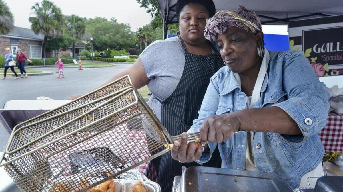 Helen P. Warren pours out some friend shrimp as her niece Bridget Frazier looks on at the Gullah Fried Sweet food booth during the 2016 Original Gullah Festival.