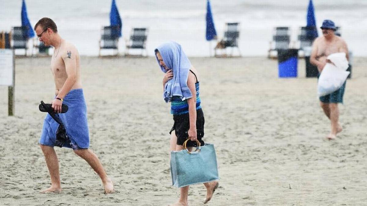 Brett Pason and his mother, Darlene, of Cleveland, Ohio, head for shelter as another rain squall spawned by Tropical Storm Isaac hits Hilton Head Island's Coligny Beach on June 13, 2016.