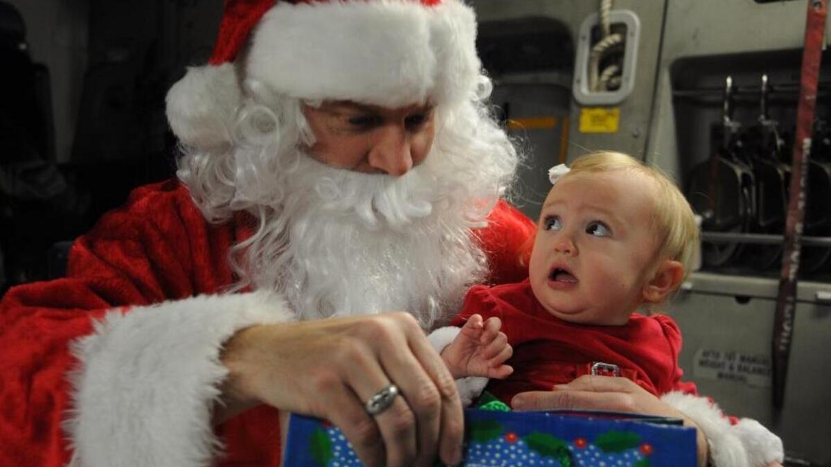 Santa Claus delivers a present to his adorable new friend Dec. 10, 2011 at Joint Base Charleston, S.C.; however, this pretty little girl is still trying to figure out what this Santa stuff is all about.