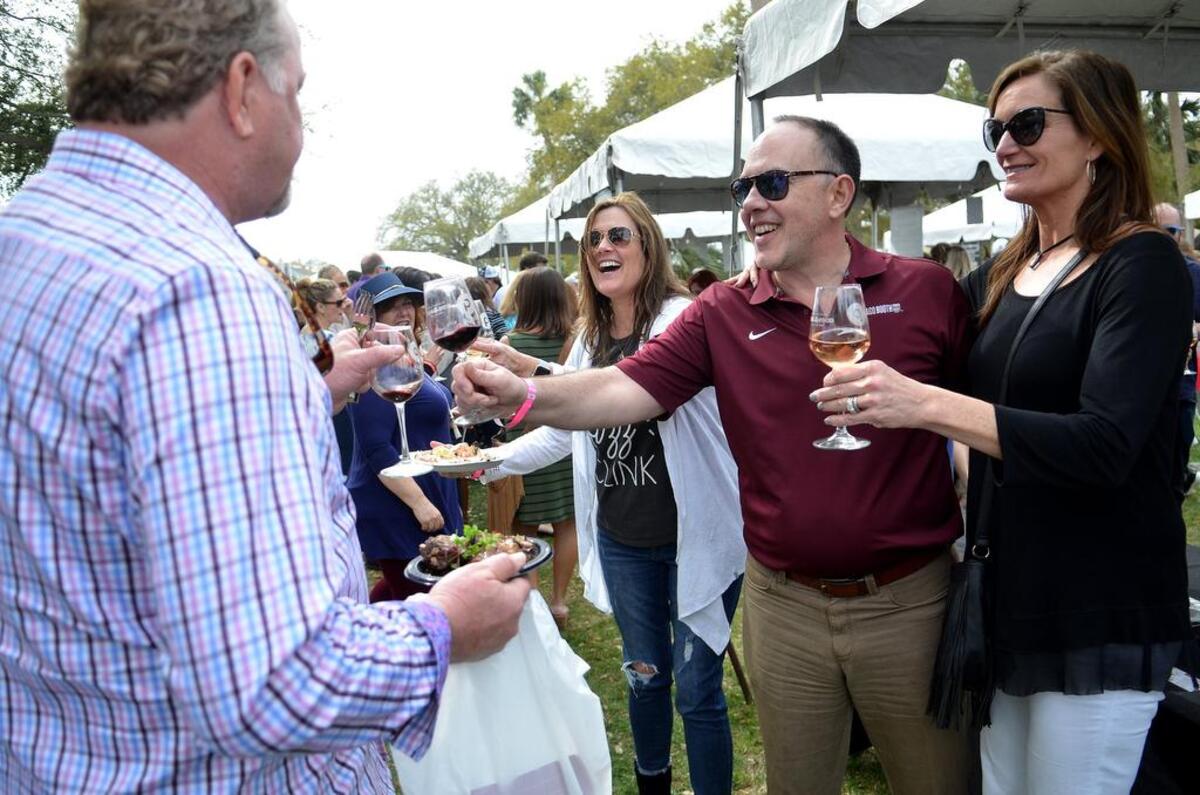 Doug Polizzi, center right, of Atlanta, along with his wife Susan and friend Annie Wehr, far right, cheers his drink to strangers as they walk by during the 2018 Hilton Head Island Food and Wine Festival at Harbour Town on Hilton Head.
