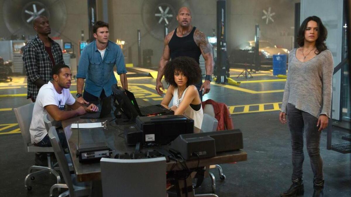 Ludacris Bridges, seated left, and Nathalie Emmanuel, seated right, and, standing from left, Tyrese Gibson, Scott Eastwood, Dwayne Johnson and Michelle Rodriguez star in “The Fate of the Furious.”