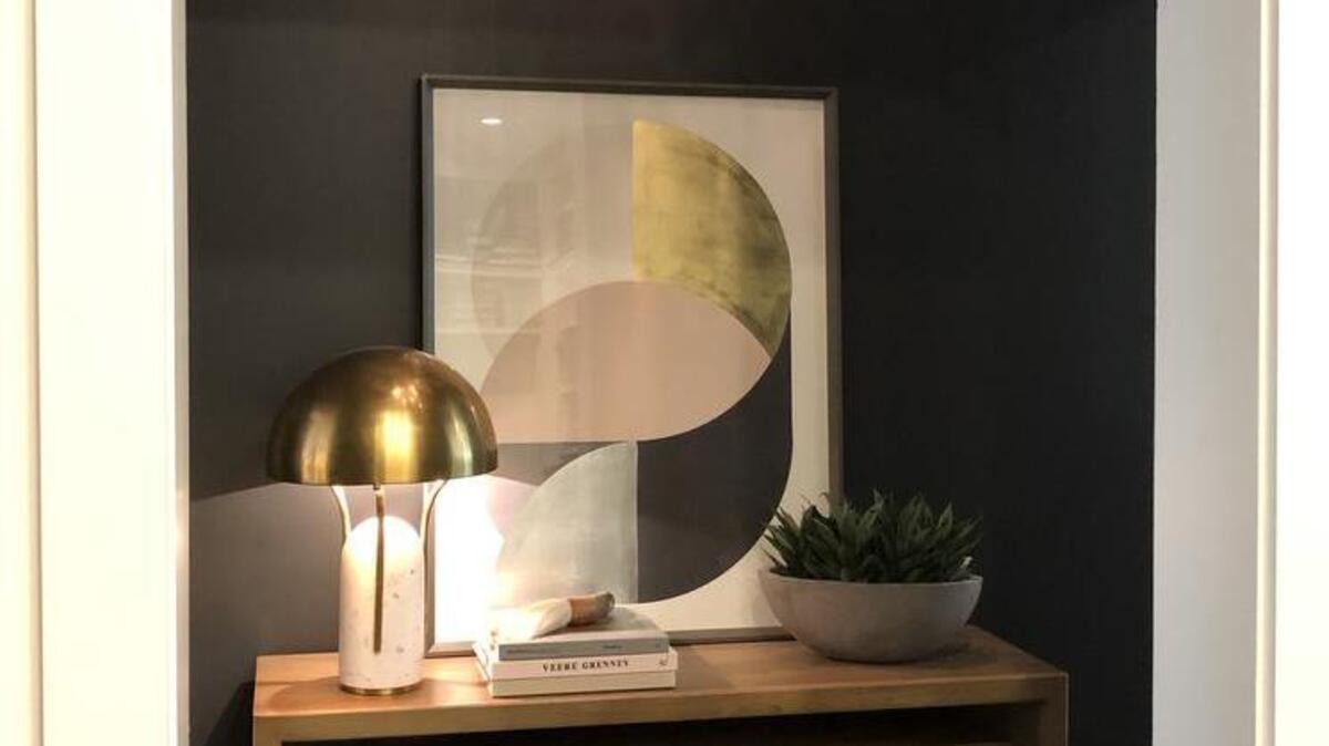 The dark wall color (Sherwin Williams Iron Ore) helps to visually expand this narrow entryway. The warm, saturated, almost black hue makes the wall appear to recede, allowing the eyes to focus on the spectacular light fixture and the sleek wood console. Painting the baseboard the same color further blurs the boundaries.