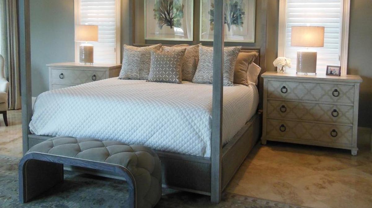 There’s nothing “girly” about the handsome canopy bed in this Colleton River Club master bedroom. Custom ordered with a warm gray finish and quilted fabric inserts, this stately bed is fit for a king or queen and balances the whimsical painted nightstands.