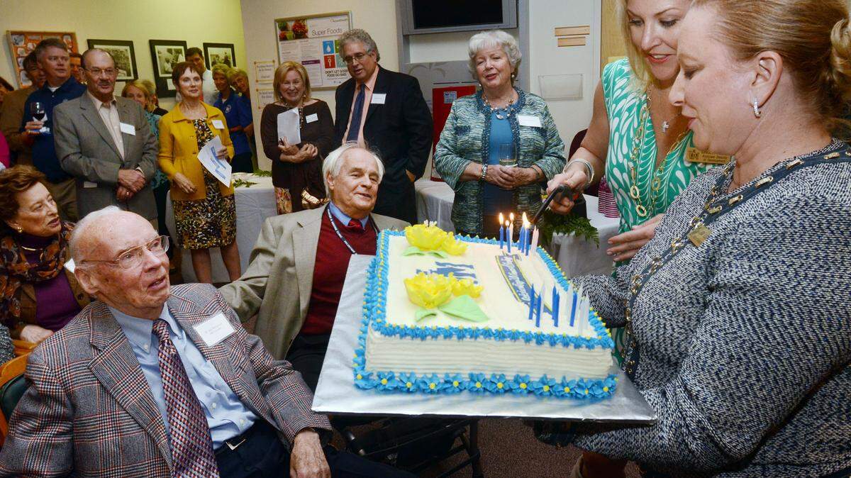 From left, Volunteers in Medicine clinic founder Jack McConnell and interim medical director Roger Sorg look on as assistant director of development Ginger Allen and director of development Linda Bloom light the candles on a birthday cake during the Volunteers in Medicine Millenium Club reception in honor of the organization's 20th anniversary.