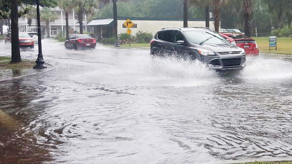 Vehicles make their way through a flooded intersection at Pigeon Point Road and Boundary Street during the afternoon of July 28, 2014. Wednesday will bring new costs to many local homeowners already burdened by high flood insurance, local realtors say.