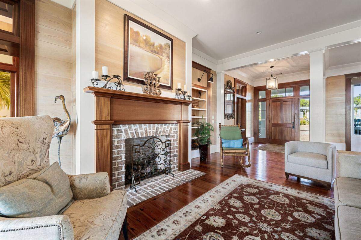 The living room at 107 Okatie Highway features a fireplace with masonry surround, open shelving built-ins and a wall of glass French doors that open onto the porch.