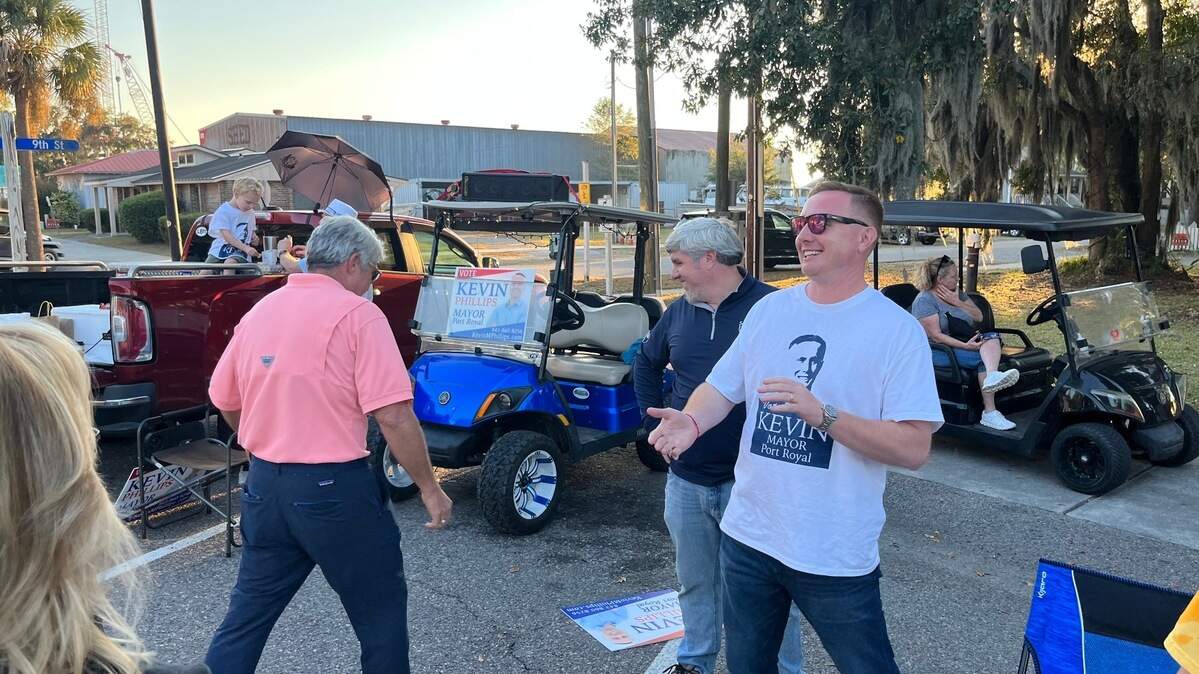 Port Royal mayoral candidate Kevin Phillips, right, shares a light moment with his supporters as he campaigns along Paris Avenue Tuesday afternoon.