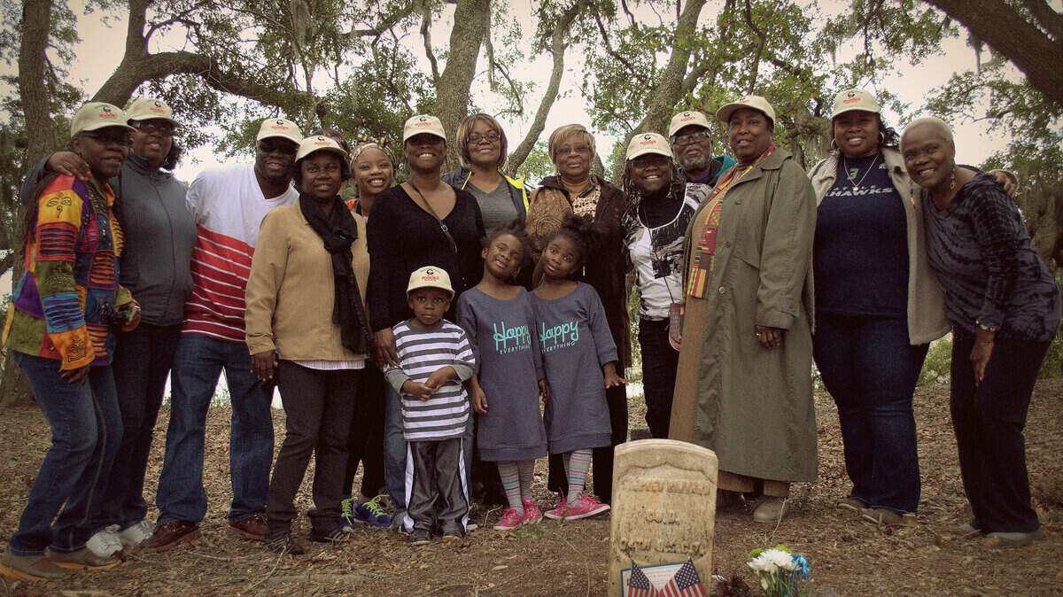 Akousa Moore, center, black shirt and white hat, is pictured with family at the grave of ancestor Stephen Binyard at Marine Corps Air Station Beaufort.