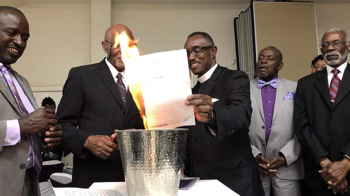 The Rev. Jon. R. Black, pastor of Bluffton’s Campbell Chapel AME Church, holds the church’s mortgage in a mortgage burning ceremony after an anonymous donor gave over half a million dollars to the church.