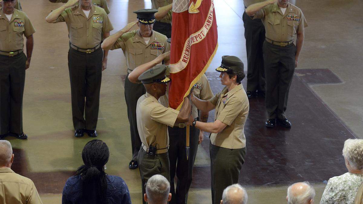 Brig. Gen. Lori Reynolds hands the Marine Corps colors to Brig. Gen. Terry Williams, signifying her officially handing over command during the change of command ceremony the afternoon of June 20, 2014, in the All Weather Training Facility on Marine Corps Recruit Depot Parris Island.