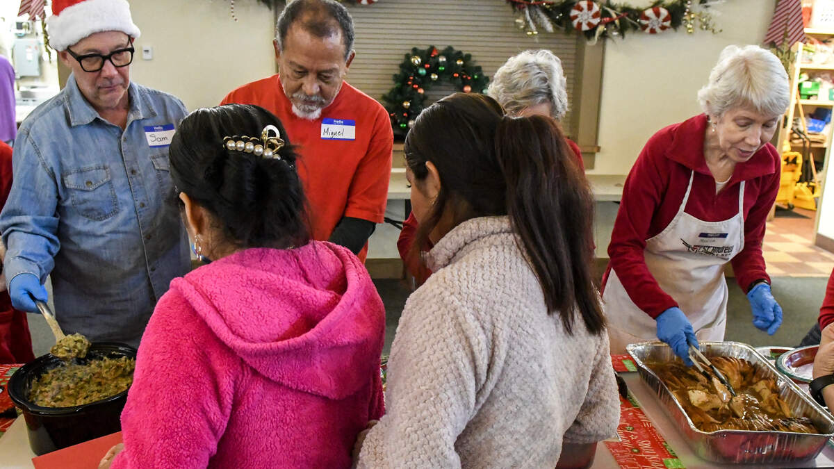 Volunteers at the Soup Kitchen serve food on Friday, Dec. 20, 2024, as Jesús Parra, and his son, Jesús, serenade those with their violins at St. Andrew By-The-Sea United Methodist Church on Hilton Head Island.