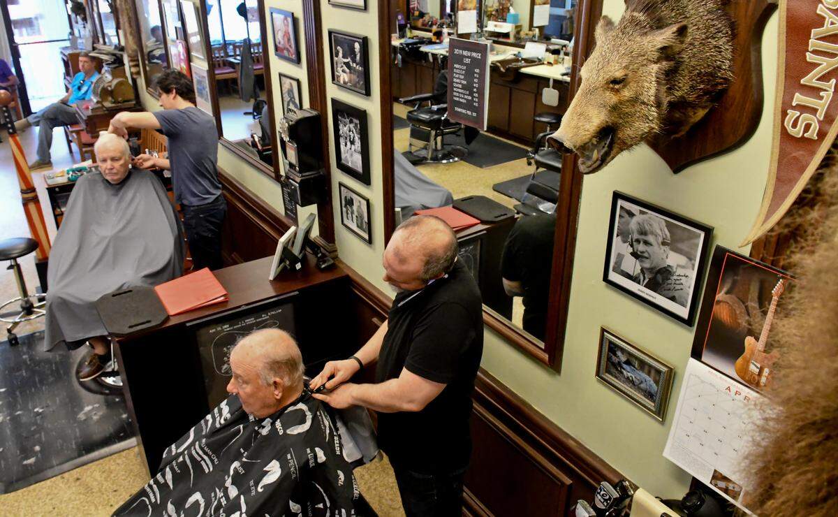 Several customers wait in line Monday morning at The Barber Shop on Mathews Drive on Hilton Head Island as barber David Butler, front, and barber Jesse Tramuta, center, cut hair. Owners of the barber shop have been told they have 45 days to leave the location that they’ve called home for more than 30 years.