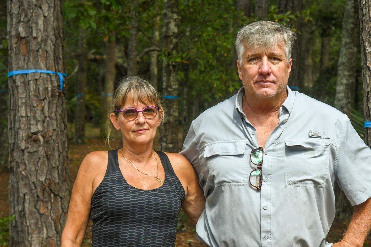 Lora Jean Knoppel and her husband Jim Knoppel are photographed on Thursday, July 27, 2023 next to surveyed land that is historically known as Cedar Point Cemetery. The Knoppel’s believe there are more graves than the three visible headstones that remain on the property that has stopped construction of a single-family residence until the land is searched for other unmarked graves.