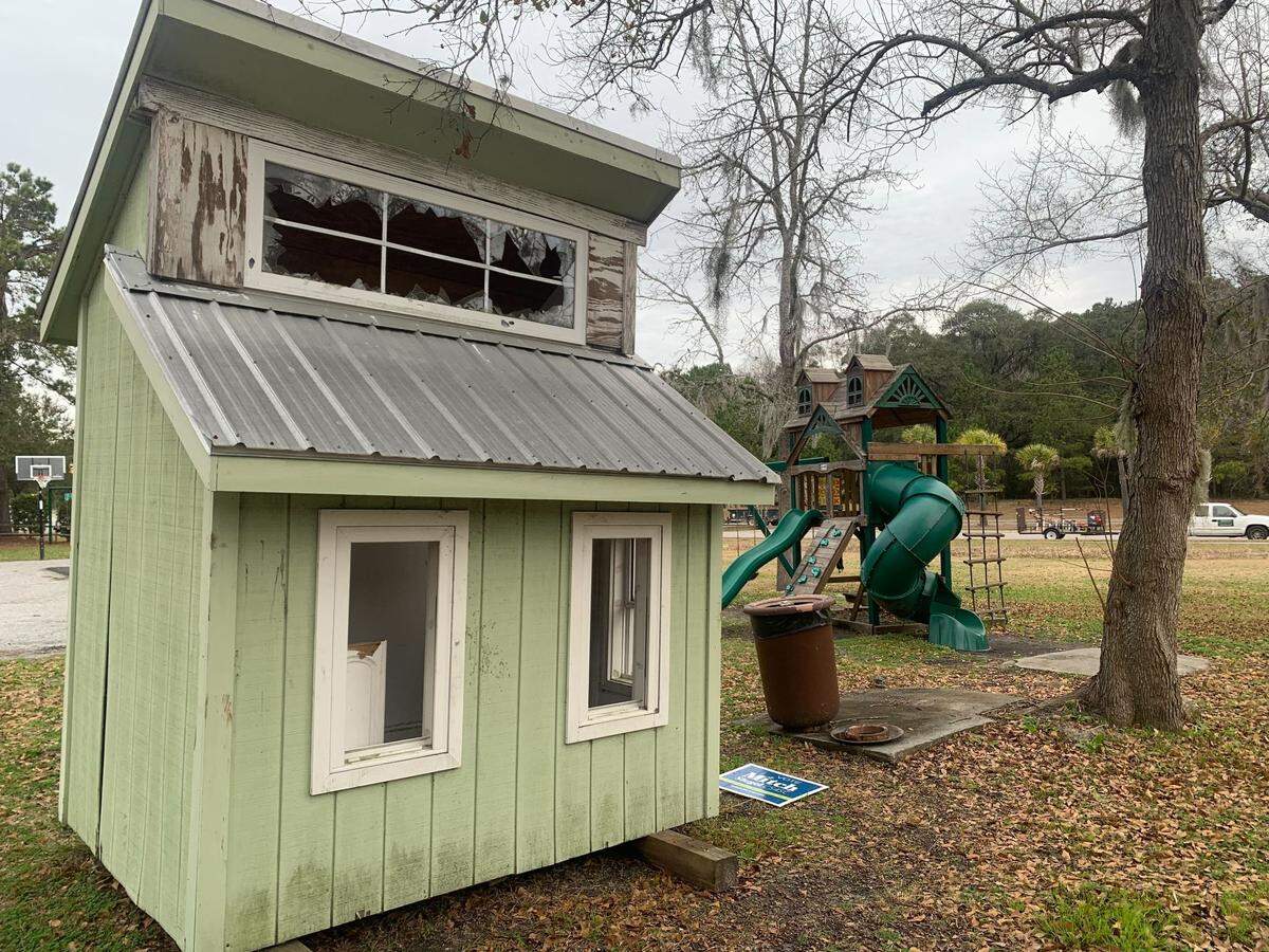 A dilapidated playhouse, with a broken window at the top, sit next to the newer playground,