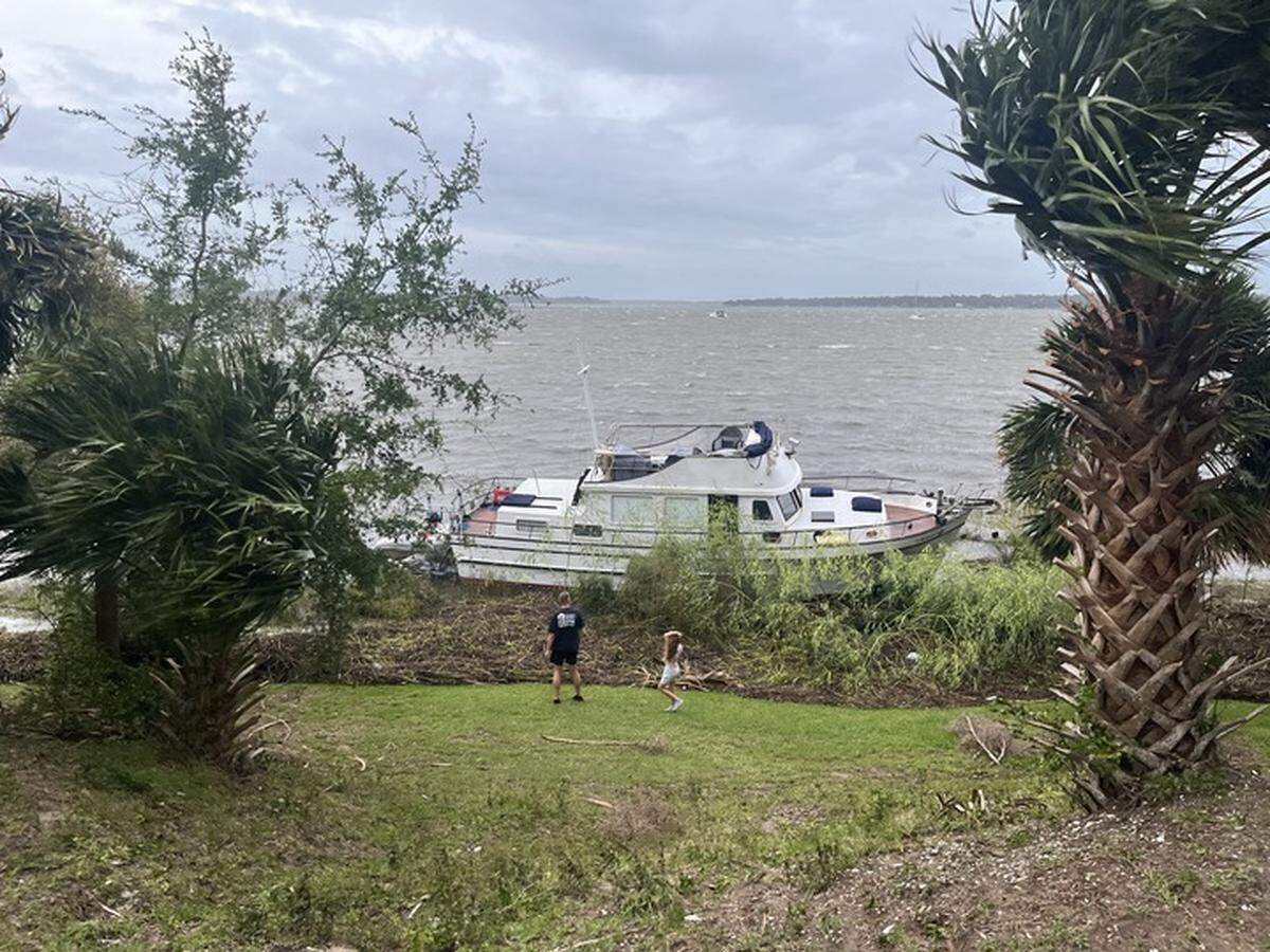 Mike Milano and his daughter check out a beached boat on the Beaufort River near his Bay Street home in Beaufort Friday morning. Tropical Storm Helene hit the city’s marina hard with boats breaking free and ending upon beached.