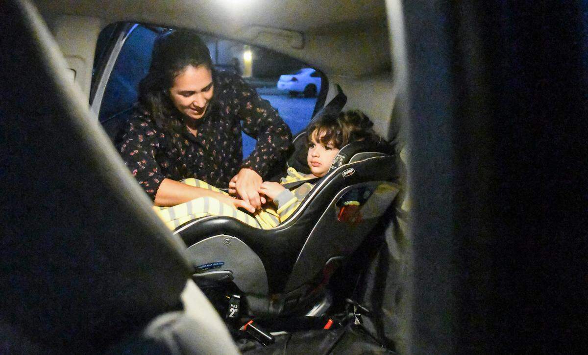 Thais Di Lazary, left, buckles her son Jonah into his car seat on Friday, Oct. 23, 2020 as they get ready to leave for the day from their apartment at Sandalwood Terrace on Hilton Head Island. “It takes one hour and three minutes to get to our destination in Beaufort,” Di Lazary said as she placed Lilo the dog in the backseat with its young master.