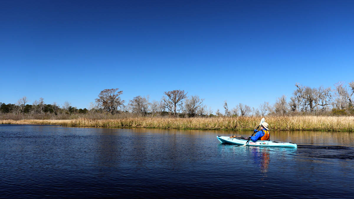 Get out there: hundreds of miles of pristine and navigable waterways make the Lowcountry a wonderful place to spend the day. Here, kayaker Alan Russell paddles across the blue, mirror-smooth surface of the Edisto River near Willtown Bluff near Adams Run, Charleston County.