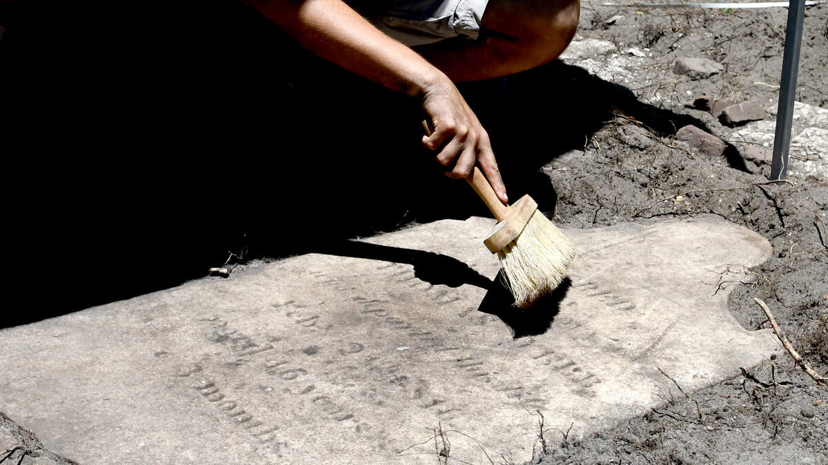 Caleb Kelly, a Bluffton High School student, brushes a headstone on Thursday afternoon that he and a group of others lead by Matthew Sanger, professor at Binghamton University unearthed at Zion Cemetery on Hilton Head Island. Sanger and his group used ground penetrating radar to survey the graveyard and found several unmarked graves and what is believed to be a family plot of the Davants, which includes this toppled headstone, from the 1800s.