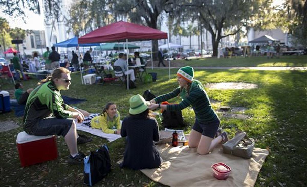 Maeve Snyder, right, places a green hat on her friend Cara Lin, center, in one of the historic squares before the start of the St. Patrick’s Day parade, Tuesday, March 17, 2015, in Savannah, Ga. Savannah has been celebrating St. Patricks Day for 191 years, there have been at least six years without a parade. (AP Photo/Stephen B. Morton)