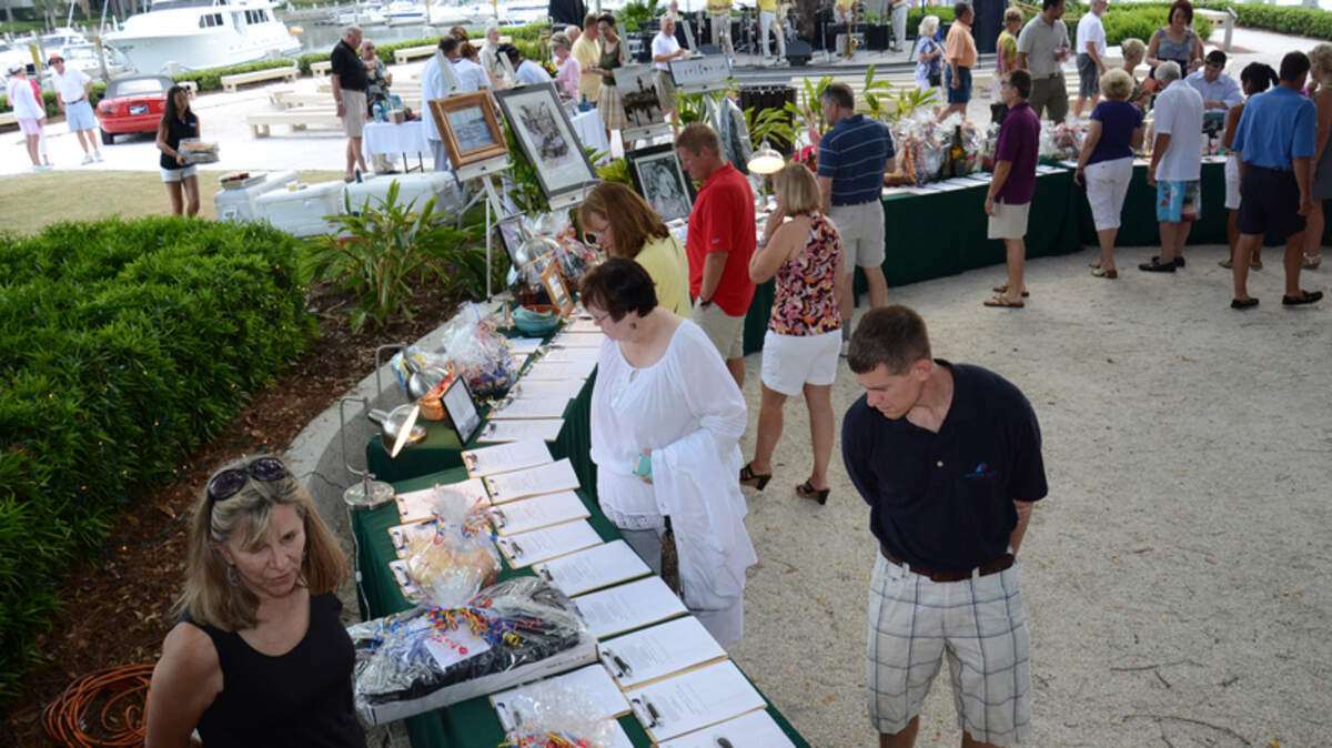 Volunteer Linda McDonald watches as guests of the eighth annual Hospice Care of the Lowcountry's Yacht Hop look over the silent-auction table Sunday afternoon at the Harbor Town Yacht Basin. All proceeds from the evening benefited the organization's patient-care programs.