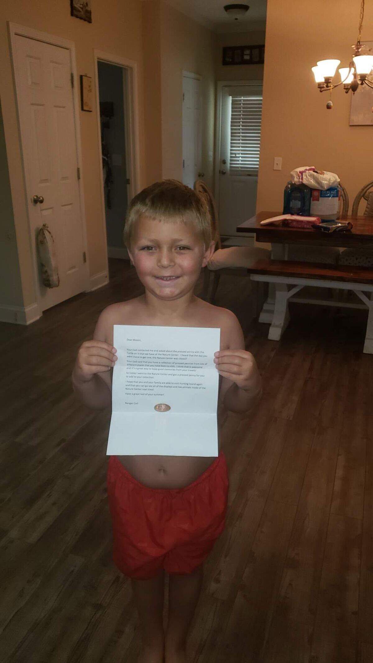 Mason Stenger poses with the pressed penny and letter a Hunting Island State Park ranger sent him.