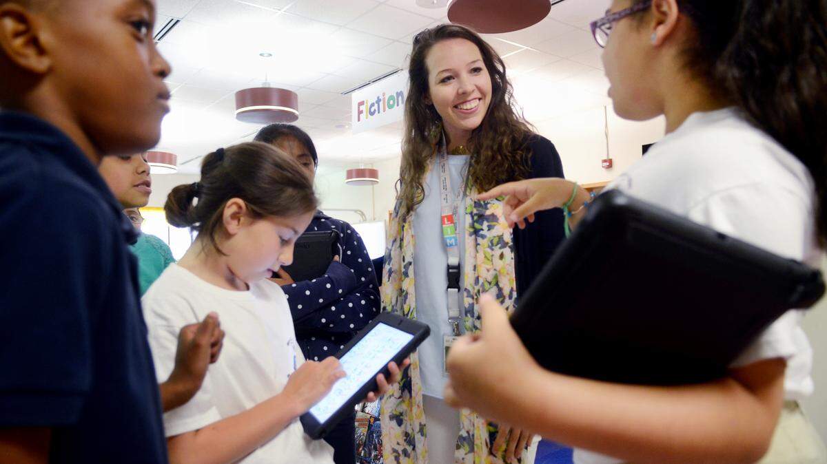 M.C. Riley Elementary School fourth-grade teacher Banks Summers talks to student Loren Pena following an activity session in the school media center on May 22.