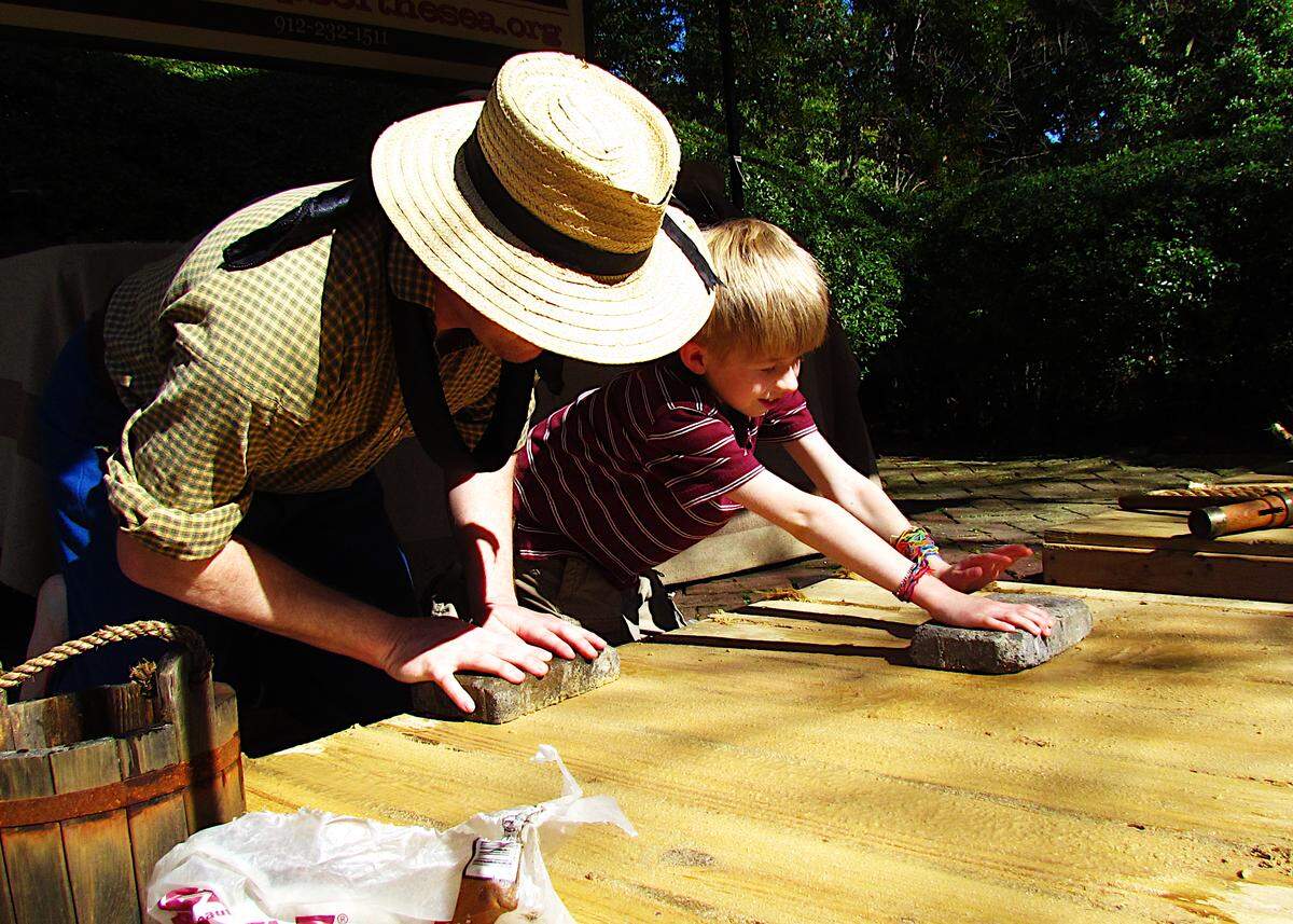 Swabbing the deck: during a special public event, a historical recreationist at the Ships of the Sea Maritime Museum in Savannah enlists the help of a young guest to provide hands-on learning and fun for all ages.