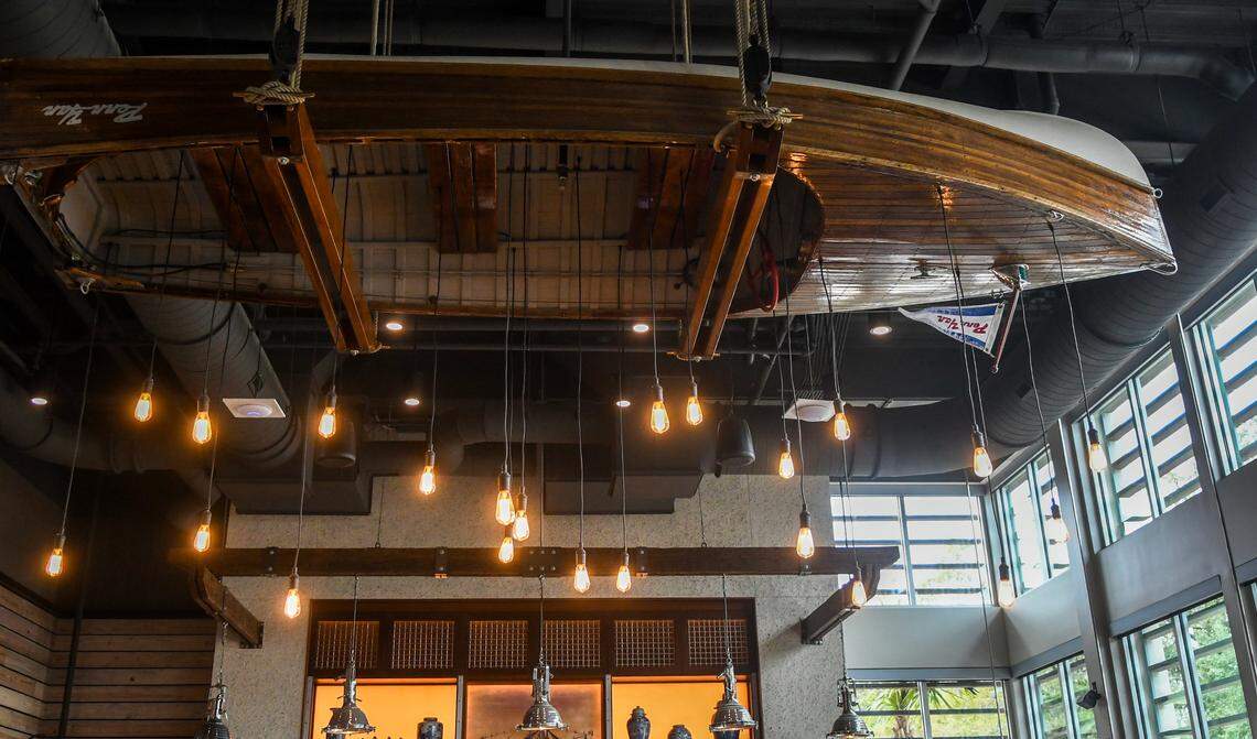 A wooden boat — a flag held horizontal at the bow — is used as a decorative light fixture near the bar at Benny’s Coastal Kitchen.