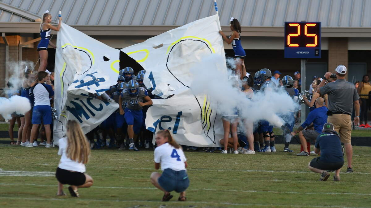 Members of the cheer squad at May River High School hold a banner honoring their fellow student Michael Mugrage, 16, with angel wings, a halo, and a number 4, who died on Aug. 28 from an aggressive form of cancer, as members of the football team crash through it to start Friday’s football game against Whale Branch Early College High School. Originally Michael, who chose the number 4, was to be an honorary captain for the team, but his deteriorating health prevented that from occurring. Instead, the football team chose to honor Michael by rotating the jersey No. 4 among players, WTOC reported.