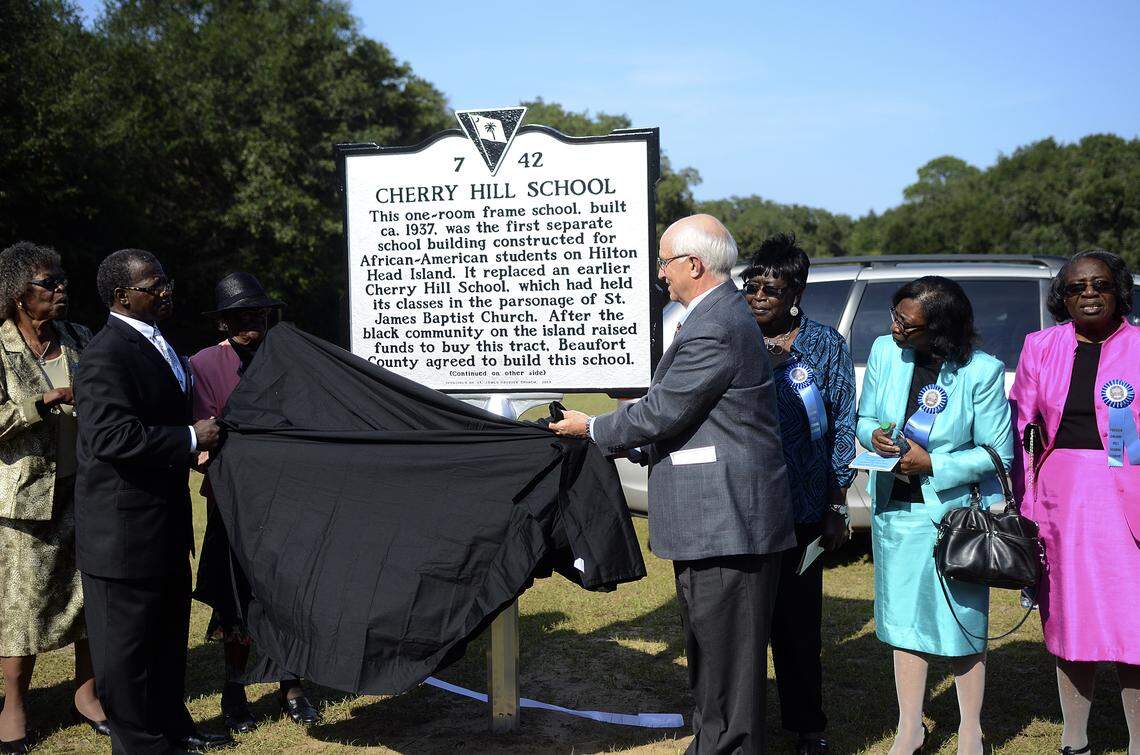 The Rev. Charles E. Hamilton Sr., pastor of St. James Baptist Church, left, and Hilton Head Island Mayor Drew Laughlin, right, unveil the South Carolina historical marker for Cherry Hill School on Sept. 20, 2013, at the school on Hilton Head Island.