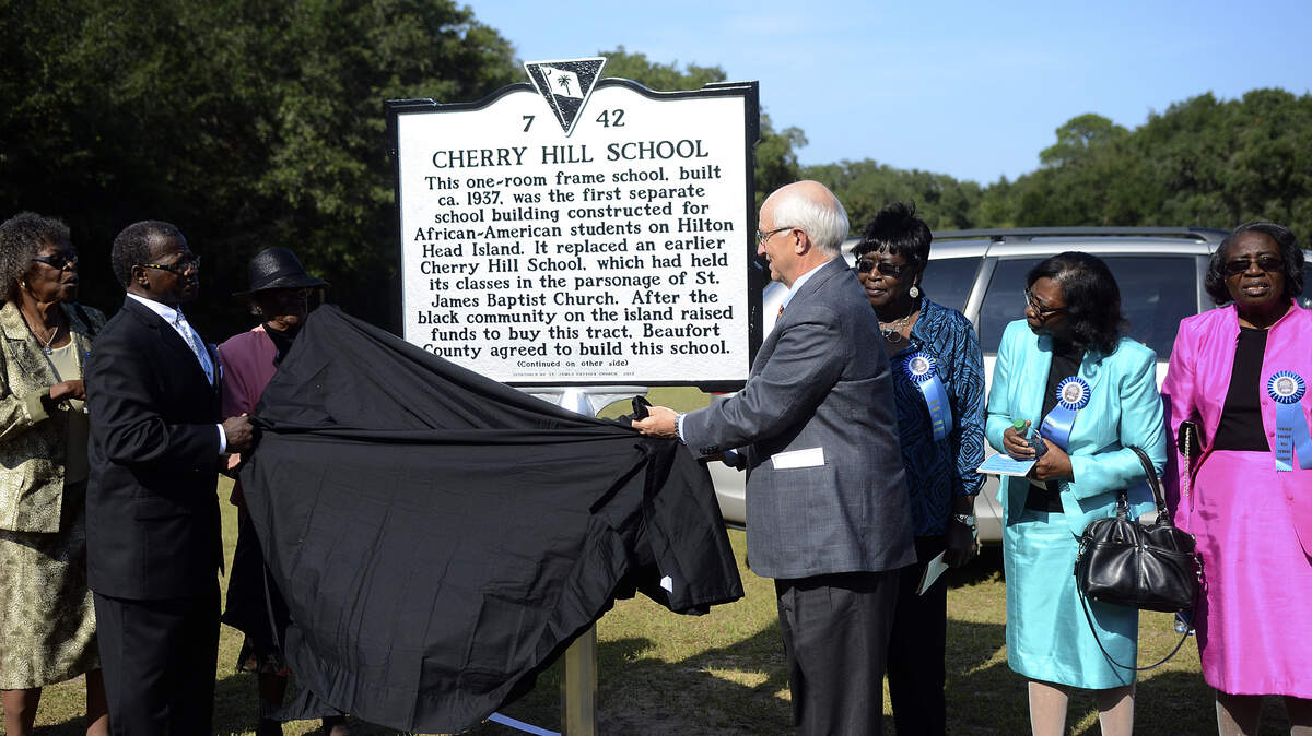 The Rev. Charles E. Hamilton Sr., pastor of St. James Baptist Church, left, and Hilton Head Island Mayor Drew Laughlin, right, unveil the South Carolina historical marker for Cherry Hill School on Sept. 20, 2013, at the school on Hilton Head Island.