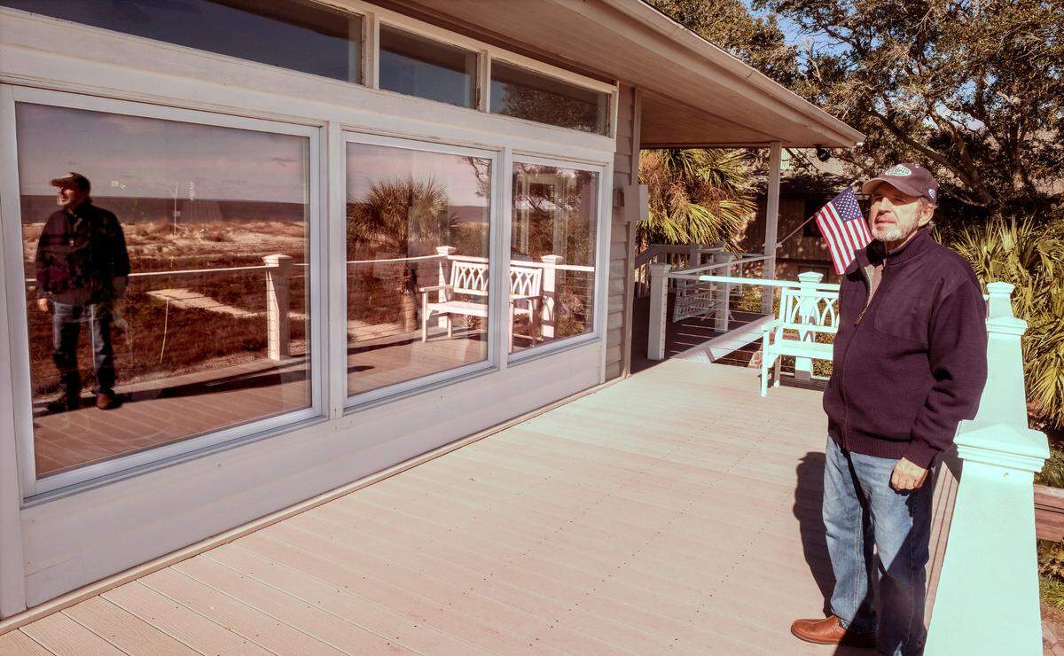 With the Atlantic Ocean and himself reflected in the windows, Al Emanuelli is pictured on Tuesday, Feb. 2, 2021 on the deck of his two-story Port Royal Plantation home on Hilton Head Island. Emanuelli - pleased with the negotiations that occurred for the new beachfront lighting to protect sea turtles - won’t have to tint his windows or buy curtains and can use lights if the lamp shade directs the light down and hides the bulb. “When my grandchildren would visit they had to use flashlights under their covers to read.” he said when talking about the former beachfront lighting rules, saying they were draconian.