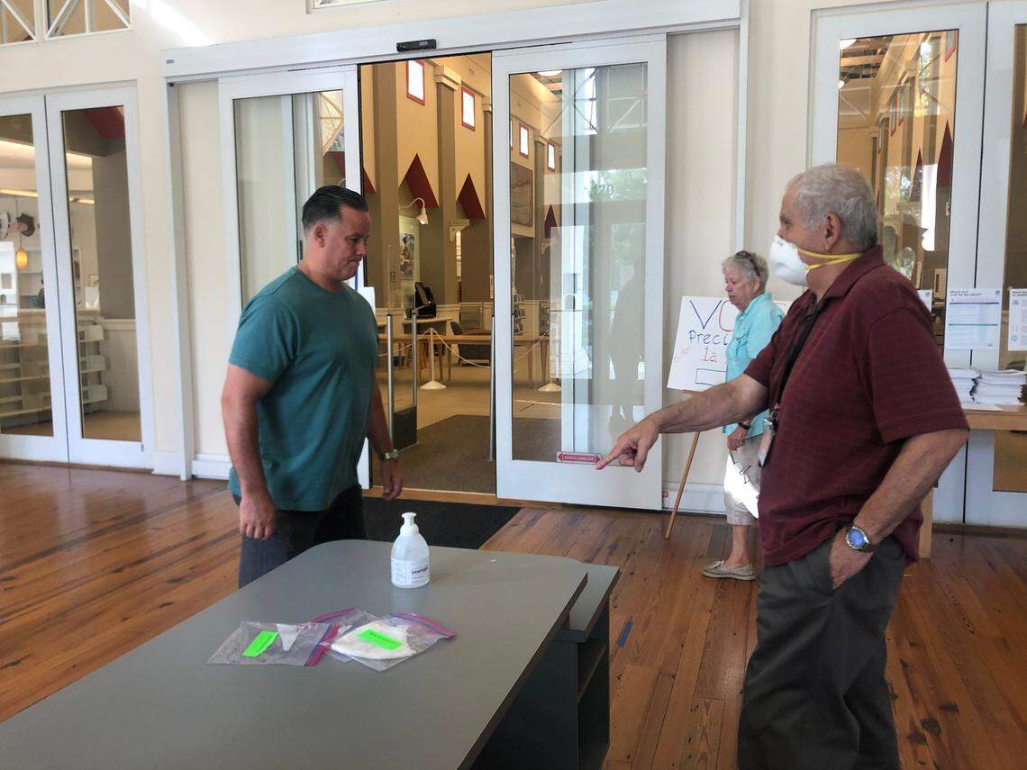 A poll worker offers a free mask and hand sanitizer to a voter at the Bluffton Library on Tuesday, June 9, 2020.