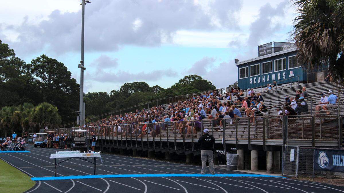 At Joe Monmonier’s celebration of life, over 400 current and former Hilton Head Island High School students, parents, teachers, and coaches fill the bleachers at the school’s football field on July 14, 2025. The athletic director of 13 years died suddenly last Wednesday.