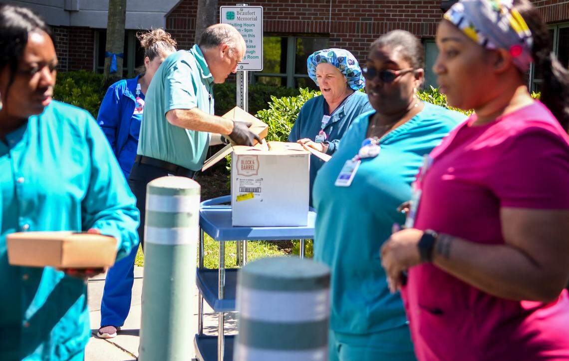 Nursing and other Beaufort Memorial Hospital staff gather at the main entrance on Friday, April 3, 2020, to pick up lunch donated by the club at Spring Island as general manager William Griffon, second from left, packs a box of food for one of the receiving departments. The gated community brought 125 boxed meals consisting of a club wrap, chips, apple and a cookie in appreciation of the hospital staff’s dedication during the coronavirus pandemic. When asked how it made one nurse feel, “It’s very humbling.” she responded.