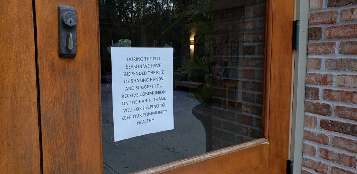 A sign on the door of St. Francis By the Sea Catholic Church informs congregants that the flu season is on hand. The Hilton Head Island church asks parishioners not to shake hands and to receive communion “on the hand.”