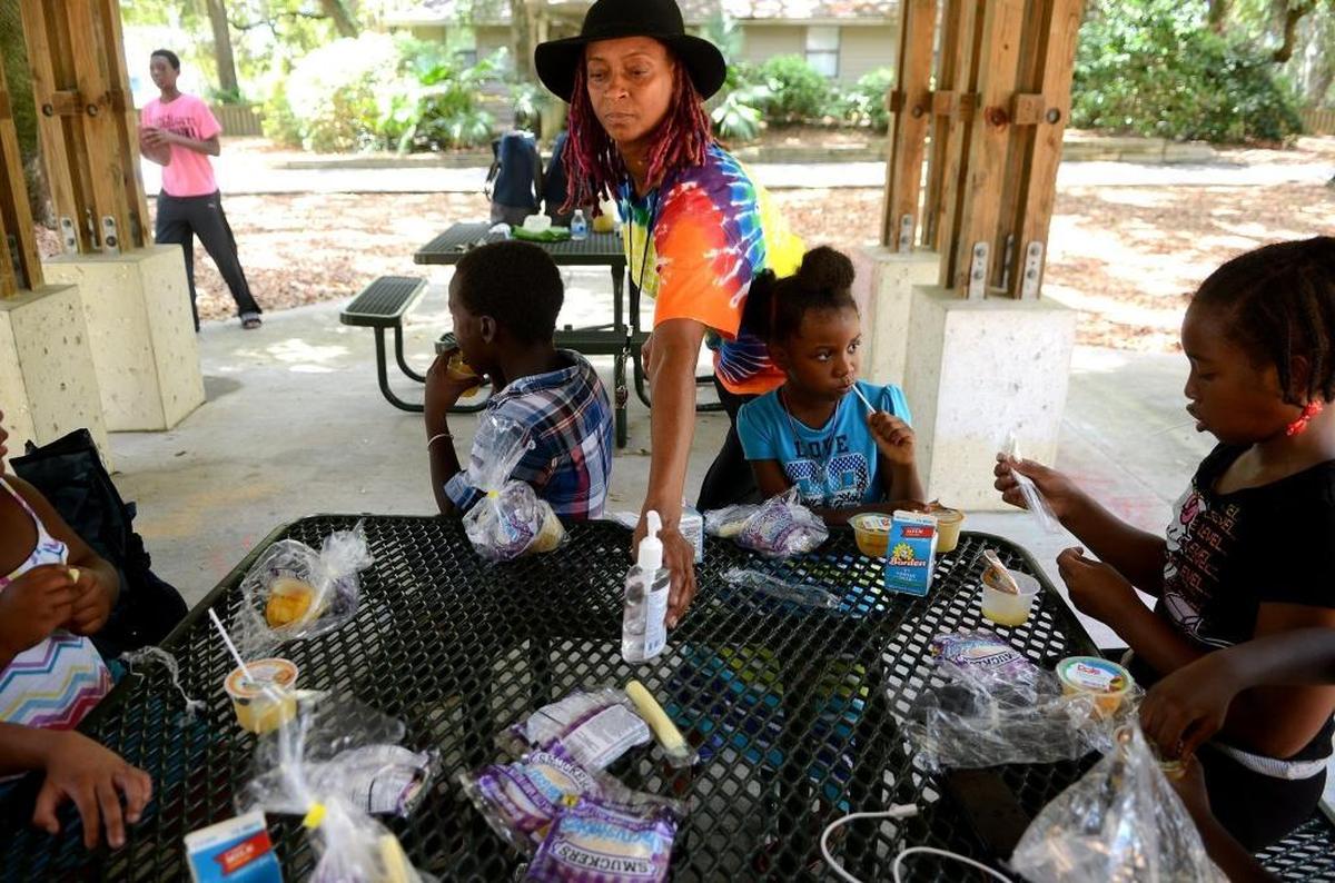Rochelle Williams, center, places some anti-bacterial hand gel on the table while local children eat their lunch provided by 12 Jewels of Life on Wednesday, August 10, 2016, under the pavilion at Green Shell Park on Hilton Head Island. The non-profit group, headed by Williams, has been at the park every week day during the summer to offer free lunches and mentoring to children in the area.