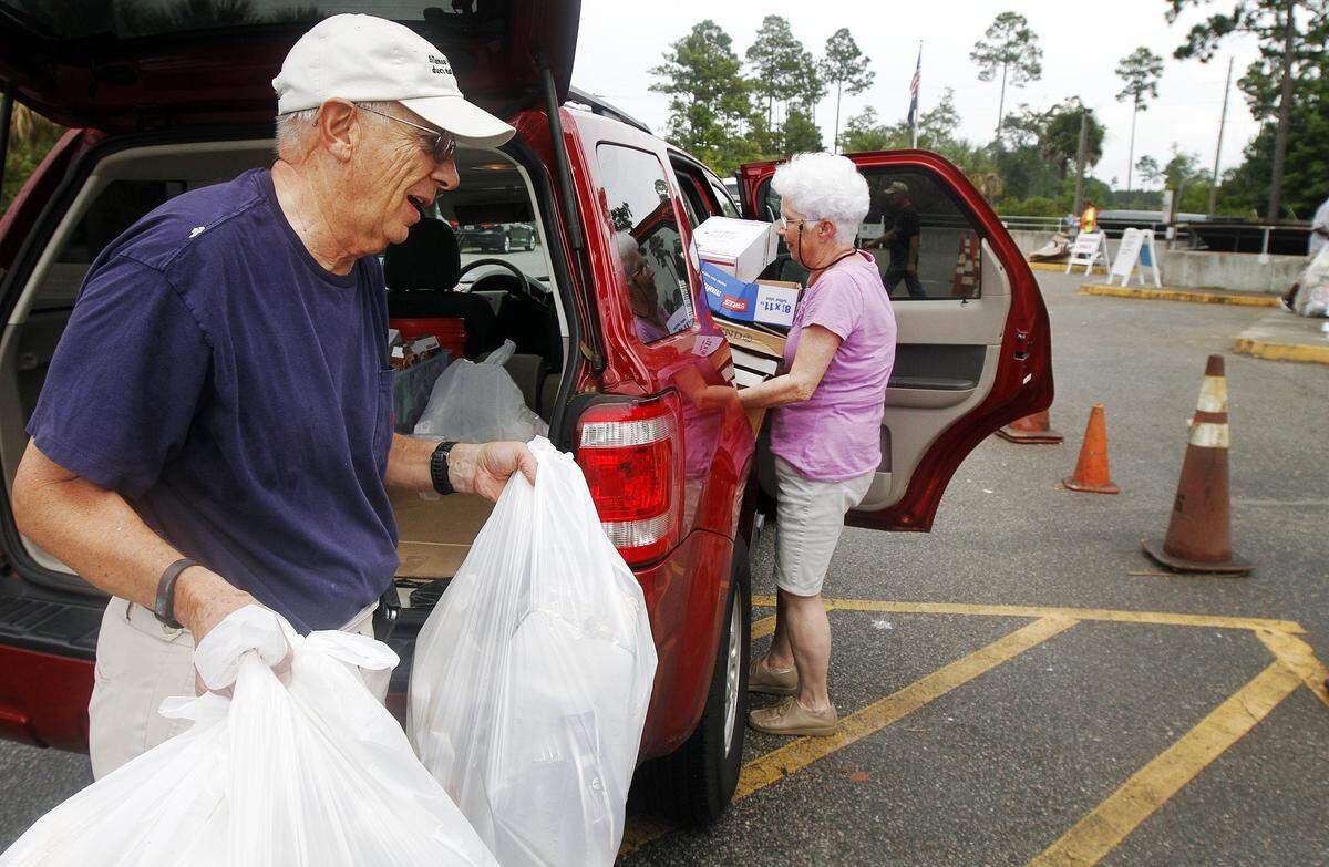 Richard and Peggy Geraghty, of Bluffton, carry trash and recyclables from their vehicle to dump at the Bluffton Convenience Center at 104 Simmonsville Road on August 1, 2014.