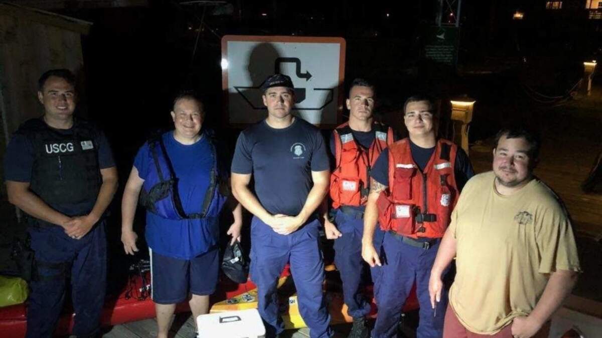 A Coast Guard crew takes a photo with two men whose kayaks capsized Wednesday, May 9, 2018, near Little Tybee Island, Georgia.