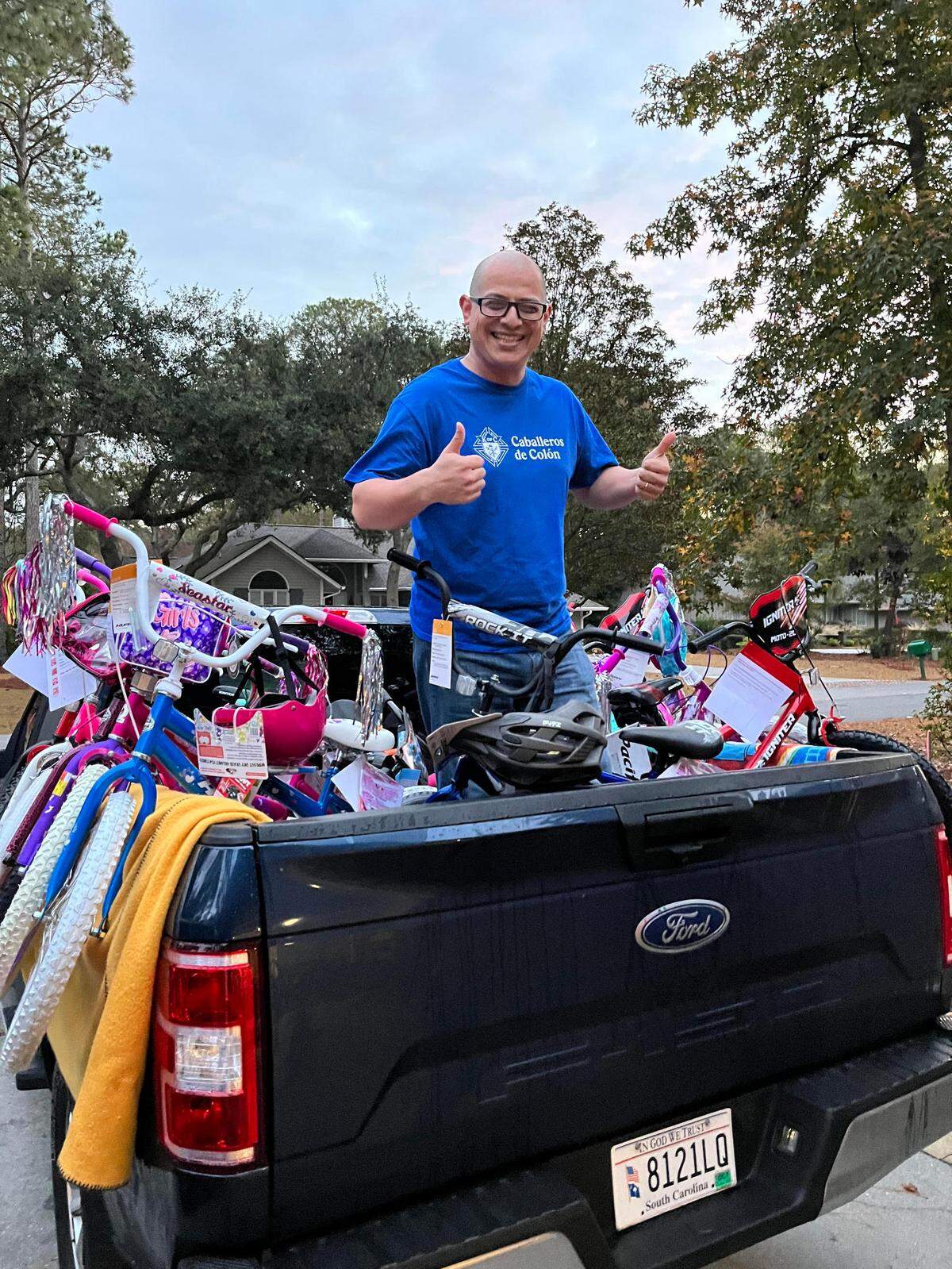 Lupe Jimenez, a knight from the Knights of Columbus, stands in the back of a pickup truck on Sunday, Dec. 19, 2021 to deliver 50 bikes to children for Christmas on Hilton Head Island.