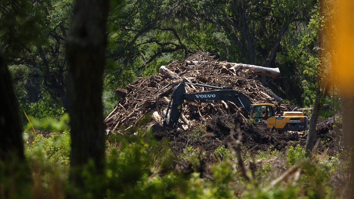 Workers move debris to a pile on the Willow Run land off of U.S. 278 in Bluffton on Tuesday afternoon.