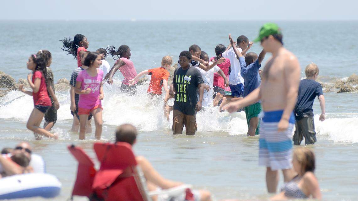 Beachgoers play in the surf earlier this summer at Hunting Island State Park.