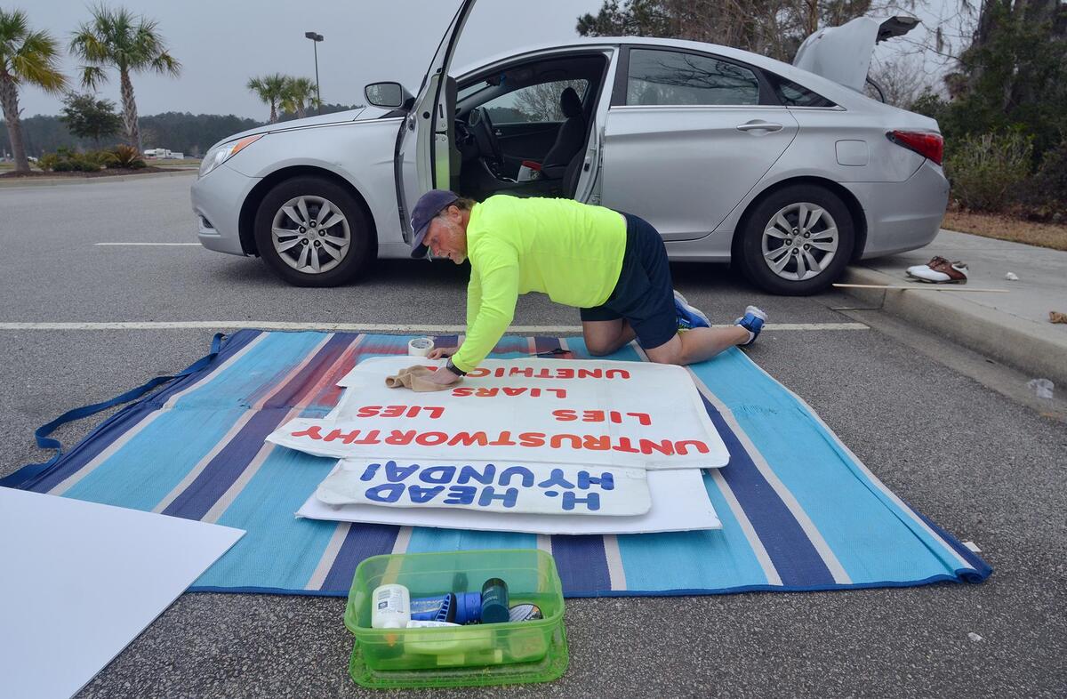 Greg Sanford Hackney cleans off one of his hand-made protest signs in a parking lot at New River Center before beginning a day of picketing in front of Hilton Head Hyundai on Feb. 14. He says the signs cost about $10 to make and, with maintenance and cleaning, can last him about three weeks. On Nov. 13, a judge ruled his actions were defamatory and not protected by the First Amendment, and ordered a stop to his protest.