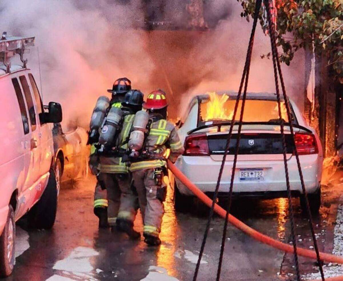 First responders from the Bluffton Township Fire District attempt to put out the flames in a car parked in the home’s driveway Sunday evening.
