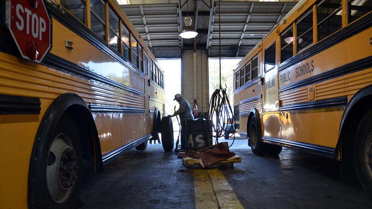 In this file photo, mechanic Eric Albertson, center, removes tires from a school bus during its yearly full maintenance check at the SC School Bus Maintenance Shop in Beaufort.
