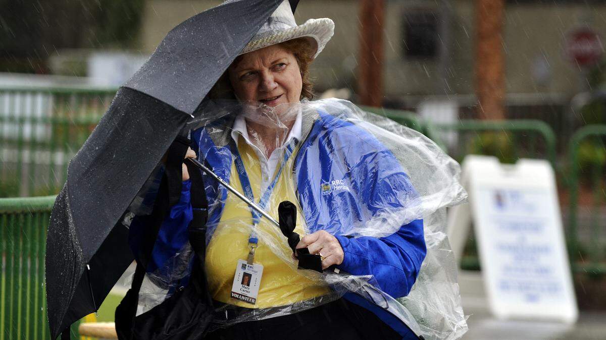 Mary Carter, a volunteer with RBC Heritage Presented by Boeing, uses an umbrella as a shield against the rain and wind while making her way through the main entrance at Harbour Town Golf Links on Tuesday afternoon.