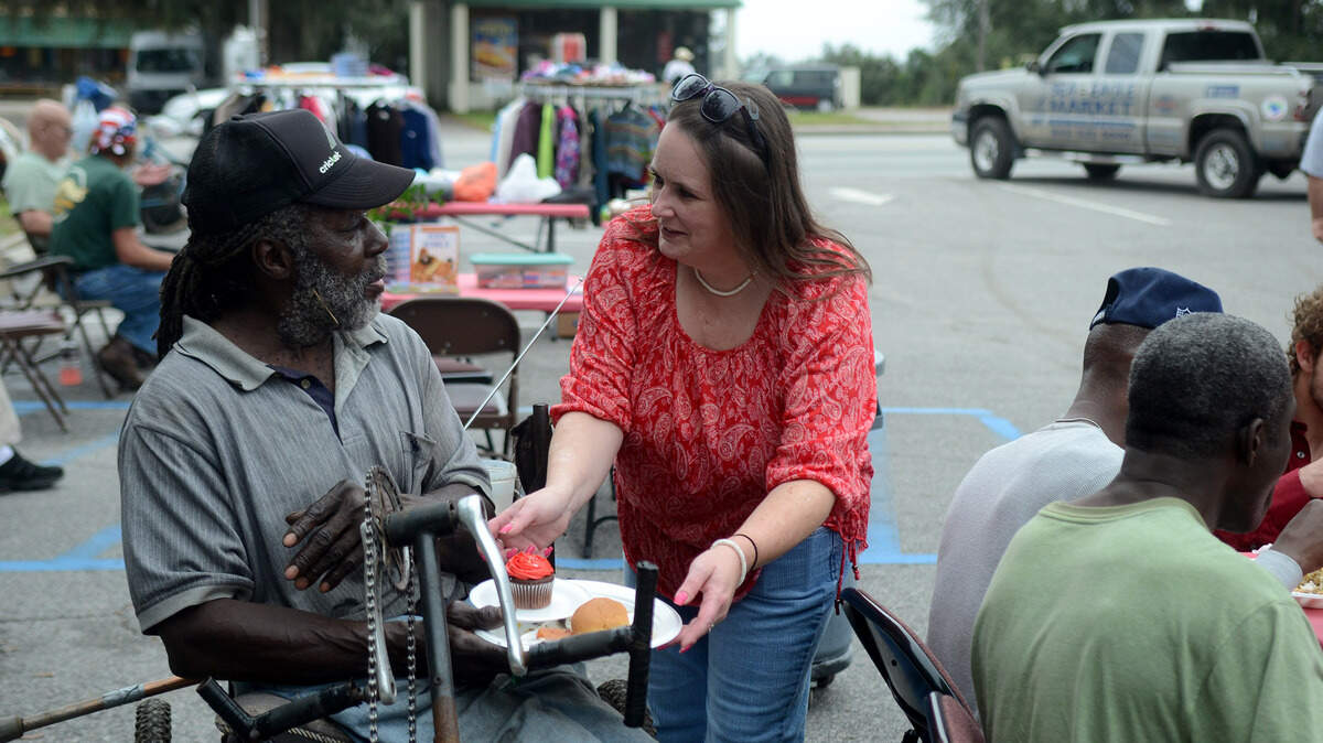 Karen Pletcher, of Beaufort, serves a cupcake to Mark Wiggs during the 4th annual Christmas dinner in the parking lot of the Atlantic Inn on Boundary Street on Friday morning in Beaufort.