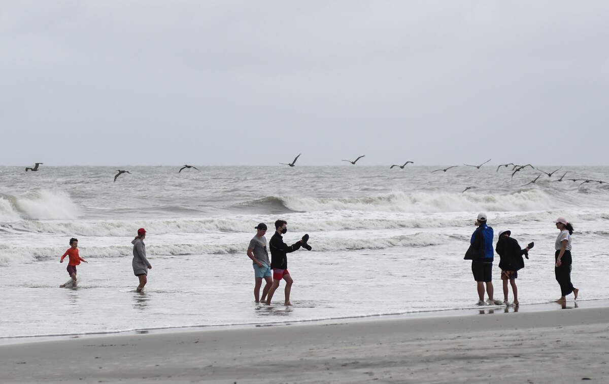 A flock of birds flies over beach goers near Coligny Beach Park on Monday, August 3, 2020 on Hilton Head Island as tropical storm Isaias churns in the Atlantic Ocean as it makes its way up the eastern seaboard.