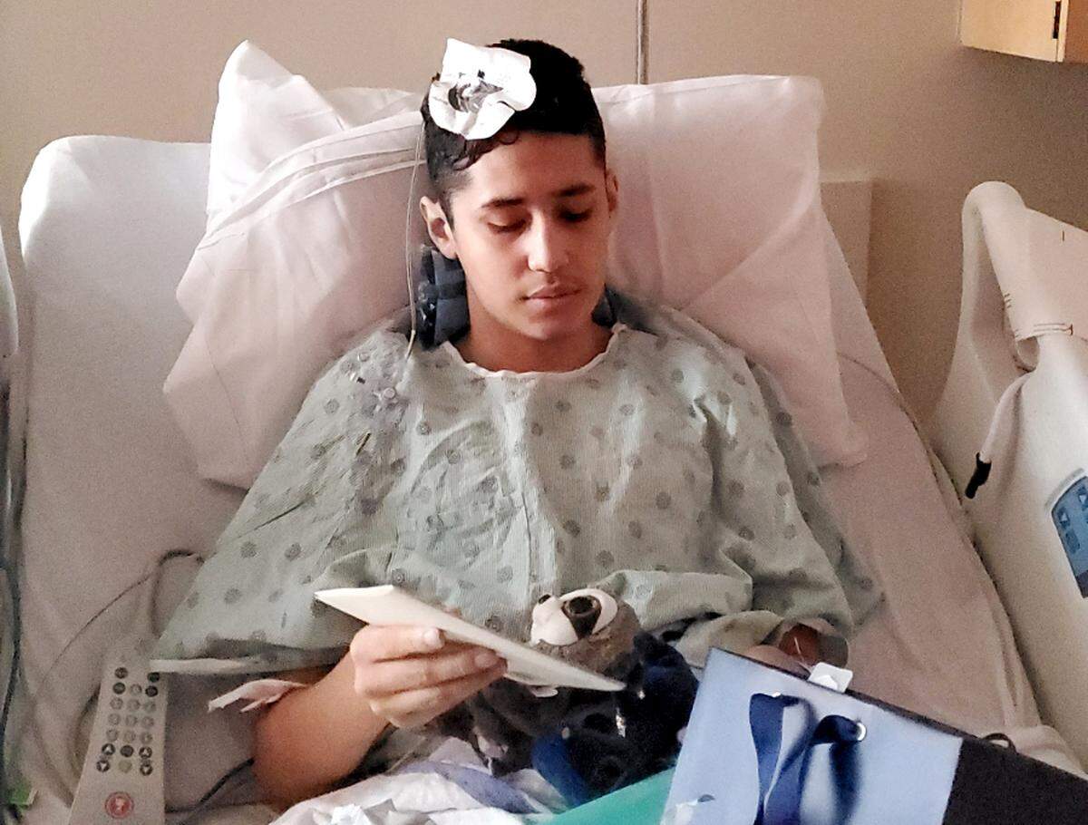 After having a large tumor removed from his head near his brain stem on July 22, 2019, at the Medical University of South Carolina in Charleston Jason Garcia, 16, opens cards after his surgery.